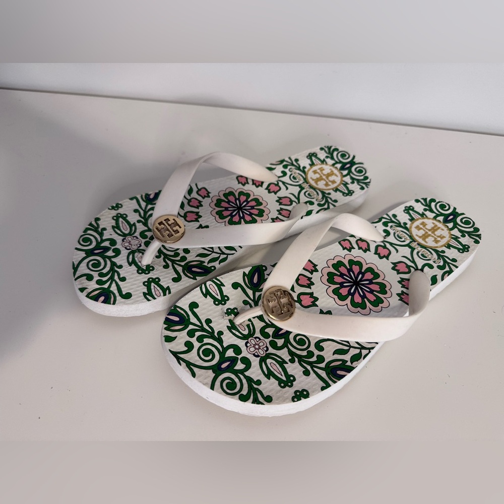 Tory Burch flip-flops has a gold-tone logo white, green, and pink floral pattern
